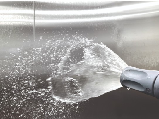 Hose nozzle spraying water into metal sink