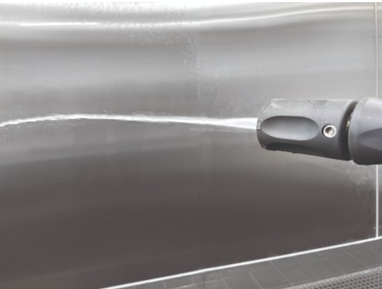 Pressure washer nozzle spraying water on surface